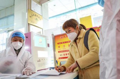 Trabajadores médicos usan vestimenta protectora al hablar con una mujer que sospecha estar infectada con el coronavirus en la estación de salud de Wuhan, China. Foto Ap