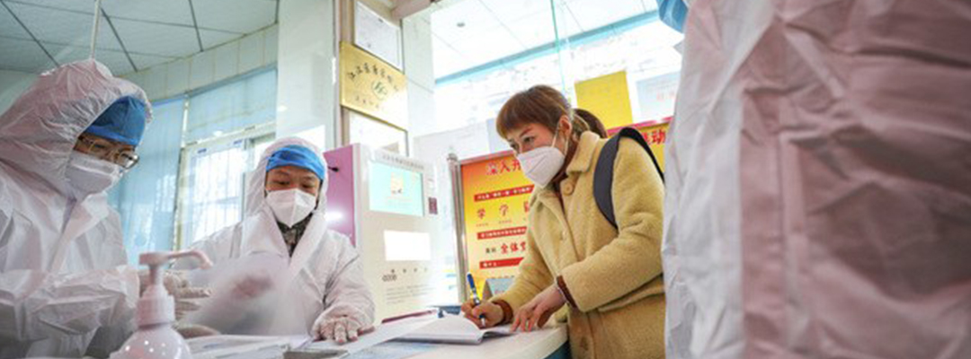 Trabajadores médicos usan vestimenta protectora al hablar con una mujer que sospecha estar infectada con el coronavirus en la estación de salud de Wuhan, China. Foto Ap