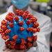 Un ingeniero muestra un modelo plástico del coronavirus en un laboratorio de Pekín, China. Foto Afp