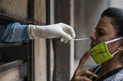 Un empleado de salud toma una muestra de una mujer para realizarle una prueba de coronavirus, en Nueva Delhi, India. Foto Afp