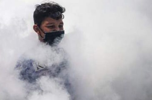 Un palestino con cubrebocas entre el humo de la fumigación contra el coronavirus en El Hebrón. Foto Afp