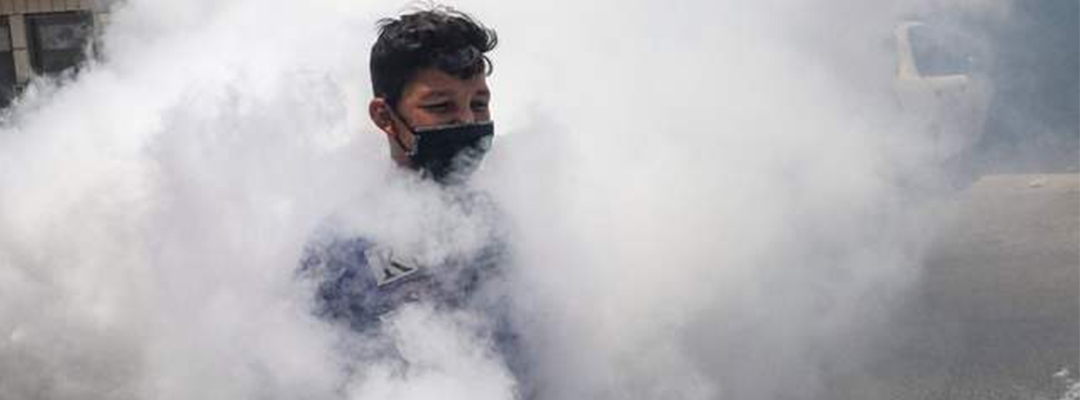 Un palestino con cubrebocas entre el humo de la fumigación contra el coronavirus en El Hebrón. Foto Afp