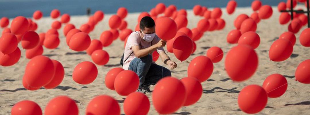 Un hombre coloca globos rojos en la arena de la playa de Copacabana en una manifestación organizada por Río de Paz para honrar a las víctimas del Covid-19. Foto AP