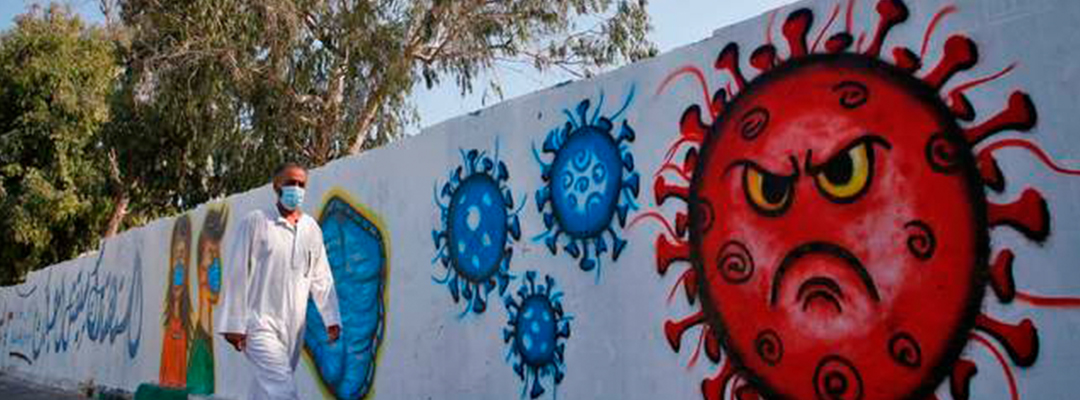 Un palestino camina junto a murales sobre el coronavirus en la franja de Gaza. Foto Afp