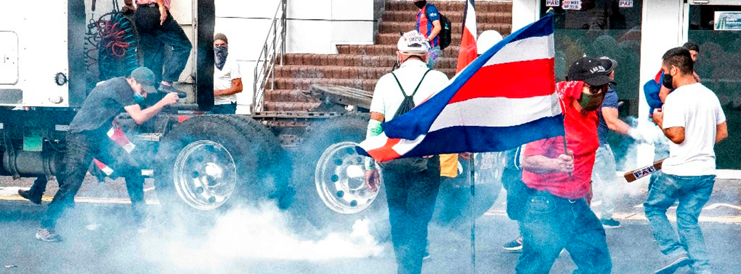 Manifestantes tratan de alejarse de gases lacrimógenos lanzados por la policía, en San José, Costa Rica, el 12 de octubre de 2020, durante protestas contra el intento del gobierno de aumentar impuestos para alcanzar un crédito del FMI. Foto Afp
