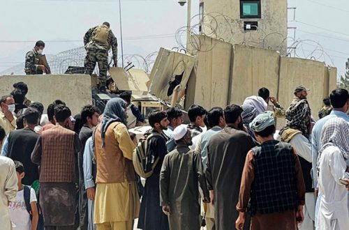 Guardias de seguridad afganos se paran en una pared mientras cientos de personas se reúnen frente al aeropuerto internacional en Kabul, Afganistán, el 17 de agosto de 2021. Foto Afp