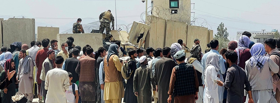 Guardias de seguridad afganos se paran en una pared mientras cientos de personas se reúnen frente al aeropuerto internacional en Kabul, Afganistán, el 17 de agosto de 2021. Foto Afp