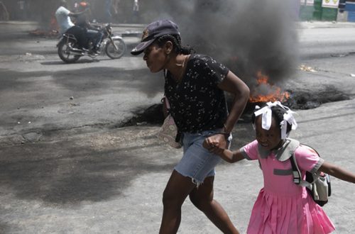 Una mujer y su hija pasan corriendo junto a barricadas, durante una protesta contra la creciente violencia en Puerto Príncipe, el pasado 29 de marzo pasado. Foto Ap