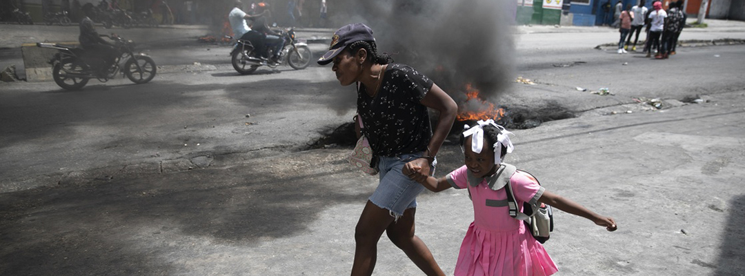Una mujer y su hija pasan corriendo junto a barricadas, durante una protesta contra la creciente violencia en Puerto Príncipe, el pasado 29 de marzo pasado. Foto Ap
